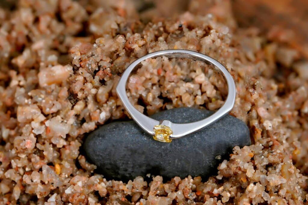 Minimal silver ring nestled in beach sand